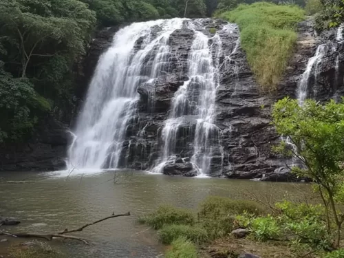 Valara Waterfalls near Munnar, cascading streams flowing over rocky cliffs into a serene pool.