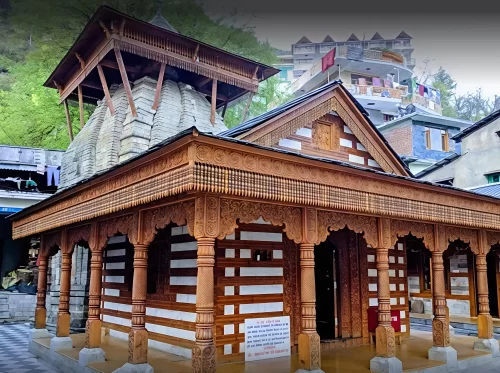 Vashishtha Temple at Manali Himachal Pradesh during cloudy weather, featuring wooden carved facade stone shikhara and village backdrop, perfect spiritual experience Himachal Pradesh tour package.