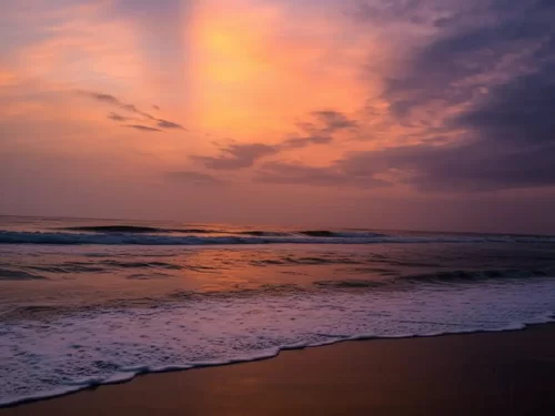 Vypin Beach in Kerala, serene shoreline with gentle waves under a colorful sunset sky.