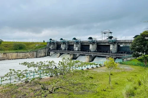 Yagachi Dam in Belur featuring open sluice gates, flowing river waters, and green embankments, perfect nature experience with Belur tour package.