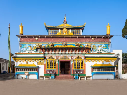 Yiga Choeling Monastery in Darjeeling during sunny daytime, featuring colorful Tibetan facade and prayer flags, perfect spiritual Darjeeling tour package