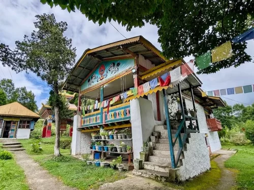 Zengbu Gompa peaceful Buddhist monastery adorned with colorful prayer flags and lush greenery in Arunachal Pradesh tour packages.