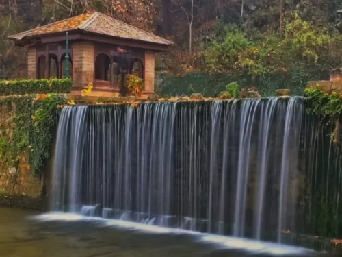 Achabal garden at Anantnag during autumn sunset, featuring terraced pavilion cascading waterfall fall leaves, perfect romantic experience Kashmir tour packages.
