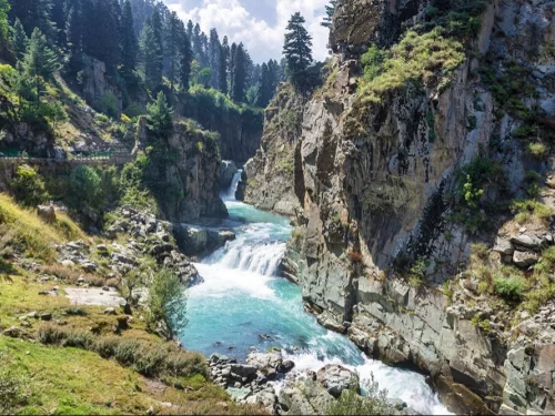 Panoramic Aharbal Waterfall Kashmir pine forest valley, turquoise cascades rocky gorge winding bridge clouds greenery, perfect Jammu Kashmir scenic waterfall nature trek package.