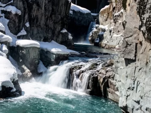 Winter wonderland Aharbal Waterfall Kashmir snow-capped gorge, icy turquoise cascades dramatic rocky cliffs frozen streams, perfect Jammu Kashmir snowy waterfall adventure package.