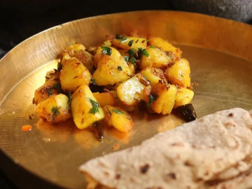 Aloo ke Gutke in spiced dry curry with cilantro garnish, authentic Indian Uttarakhandi dish, steaming hot delight.