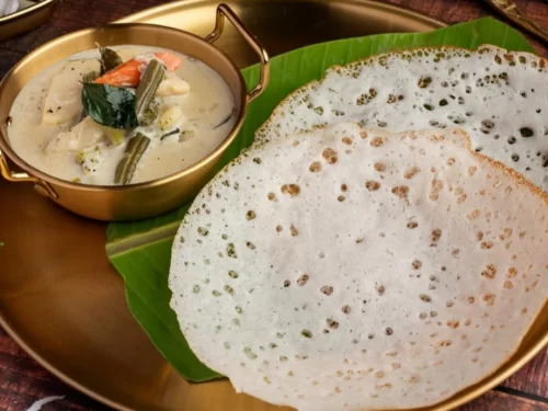 Houseboat at Alleppey backwaters during sunset, featuring palm trees and calm lagoons, romantic Kerala tour package.