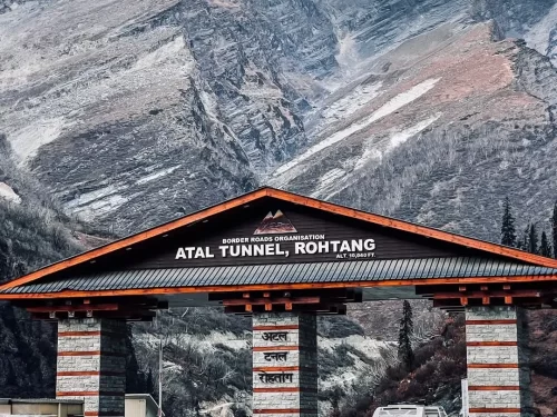 Atal Tunnel entrance gate at Rohtang in Lahaul Spiti during partly cloudy day, featuring BRO signboard, snowy mountains, perfect Manali Leh tour package.