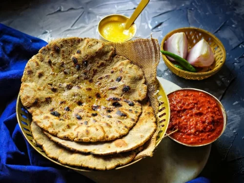 Bajra Roti in golden millet flatbread with ghee glaze and onion garnish, authentic Indian Rajasthani bread, steaming hot delight.