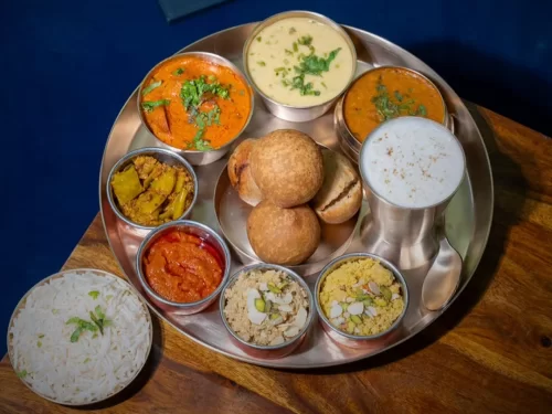 Daal Baati Churma thali with lentil dal, baked wheat balls, sweet crumbly mix, ghee and pickle sides, authentic Indian Rajasthani platter, steaming hot delight. 