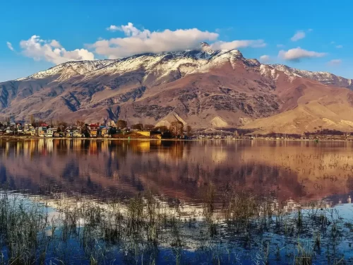 Dal Lake Srinagar with snowcapped Pir Panjal mountains houseboats shoreline reflection featured in Kashmir Srinagar houseboat tour packages