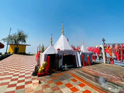 Dhwaj Temple in Pithoragarh, Uttarakhand featuring white shrines adorned with red flags on a scenic hilltop, a revered pilgrimage site included in Uttarakhand tour packages