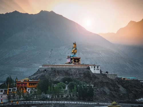 Diskit Gompa Ladakh golden green Maitreya Buddha statue sunset hilltop monasteries trees Shyok Valley rugged mountains Nubra, perfect Leh Ladakh spiritual adventure package.
