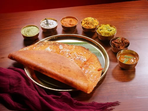 Dosa, a crispy fermented rice-lentil crepe served with coconut chutney, sambar and assorted sides, iconic South Indian breakfast staple.