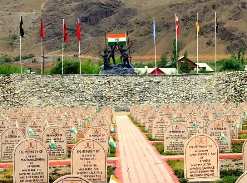 Drass Kargil War Memorial Ladakh memorial garden white headstones supreme sacrifice plaques pathway central soldier statues multiple national flags rocky mountains backdrop, honoring 1999 Kargil heroes Operation Vijay NH1D Ladakh adventure trek