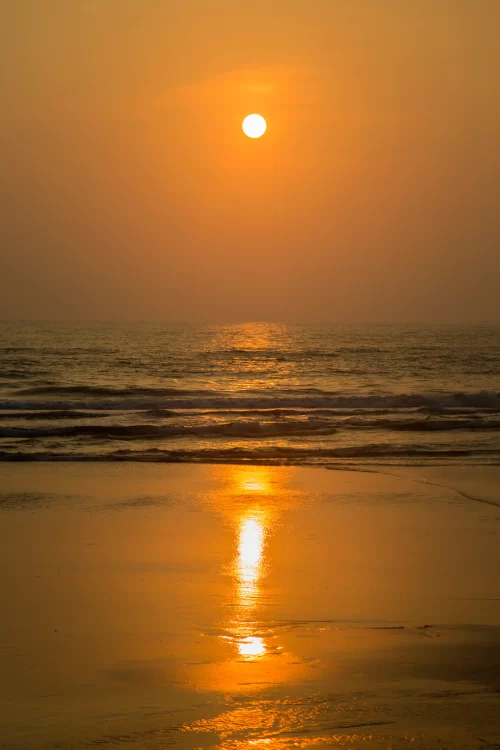Golden sunset over calm Arabian Sea waves reflecting on a serene Goa beach, a romantic coastal experience included in Goa tour packages.