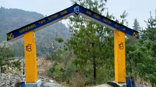 Gurudwara Tapo Asthan Sahib in Menchuka featuring blue-yellow entry arch, pine trees, and serene valley, perfect Arunachal Pradesh tour package experience.