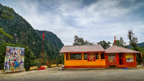 Sri Hanuman Temple featuring yellow-orange walls, religious artwork, and mountain backdrop, perfect spiritual experience with Sikkim tour package.
