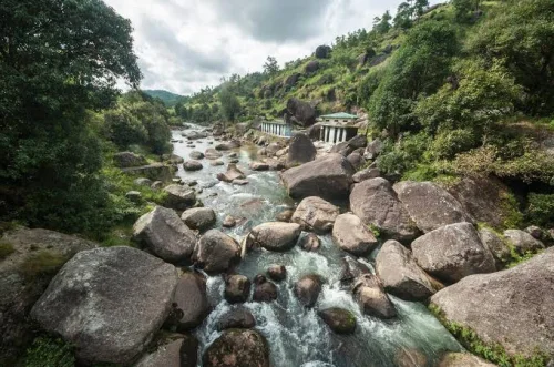 Jakrem Hot Springs near Shillong featuring a rocky riverbed, flowing natural stream, and lush green hillsides, perfect wellness experience with Meghalaya tour package. 