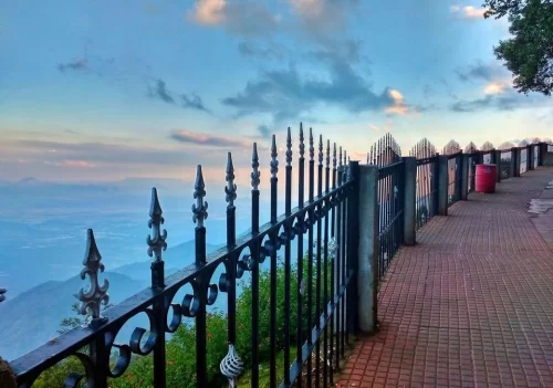 Coaker’s Walk in Kodaikanal at sunrise, featuring fenced cliffside promenade, valley views and colourful sky, perfect scenic Tamil Nadu tour package 