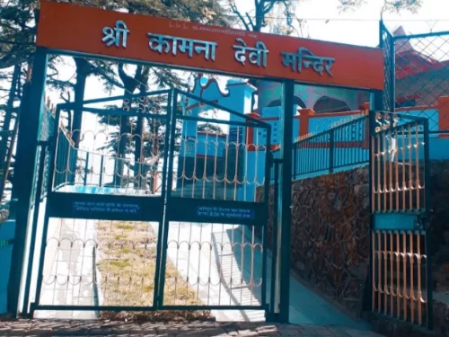 Kamna Devi Temple entrance gate in Shimla, Himachal Pradesh, featuring a turquoise-painted temple complex behind iron gates with a Hindi signboard, a popular spiritual site included in Himachal Pradesh tour packages.