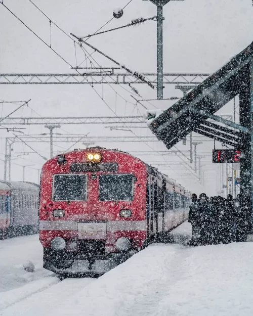 Train arriving at Srinagar Kashmir railway station during heavy snowfall, a winter travel experience in Kashmir tour packages