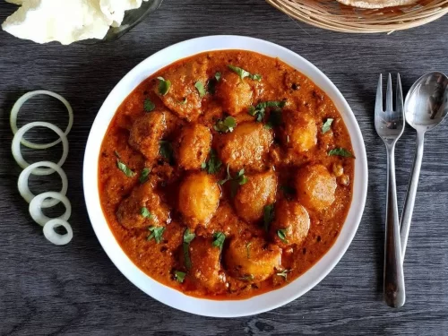 Kashmiri Dum Aloo in rich red spicy yogurt gravy with baby potatoes, garnished with fresh cilantro, authentic Indian curry.