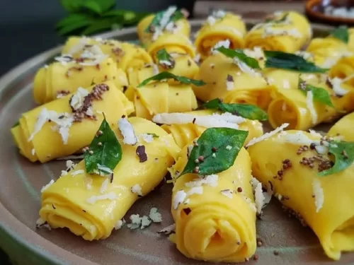 Khandvi made from gram flour rolls tempered with mustard seeds, curry leaves, and coconut, authentic Indian Gujarati snack.