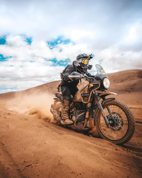 Adventure bike ride in Ladakh across rugged high-altitude terrain with dust trails and dramatic landscape, an iconic experience in Ladakh tour packages