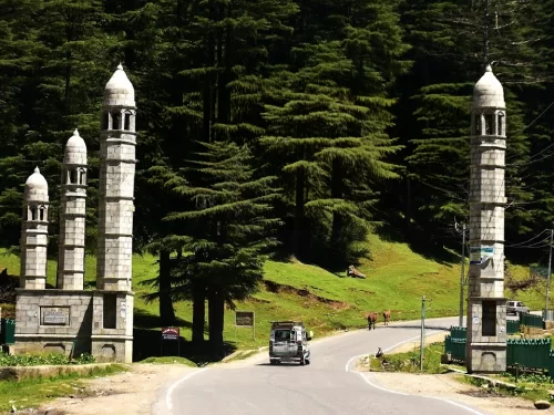 Stone minaret gate at Lolab Bungus Valley entrance during sunny day, featuring pine deodar forests road jeep, perfect adventure experience Kashmir tour packages.