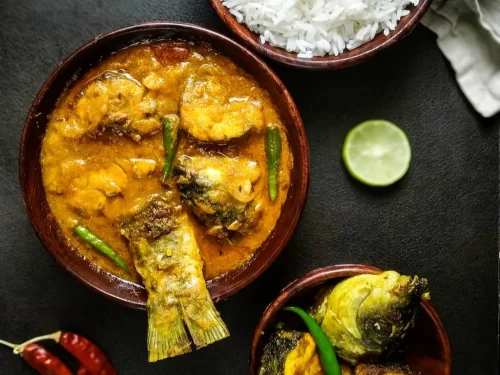 Macher Jhol in light spicy fish curry with green chilies and mustard oil, authentic Indian Bengali cuisine served with steamed rice.