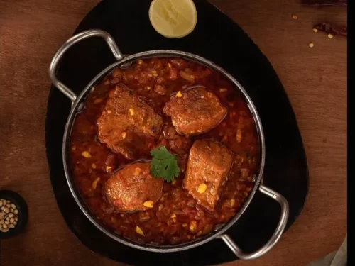 Masor Tenga in tangy tomato-based fish curry with mustard and spices, authentic Indian Assamese cuisine with light refreshing flavors.