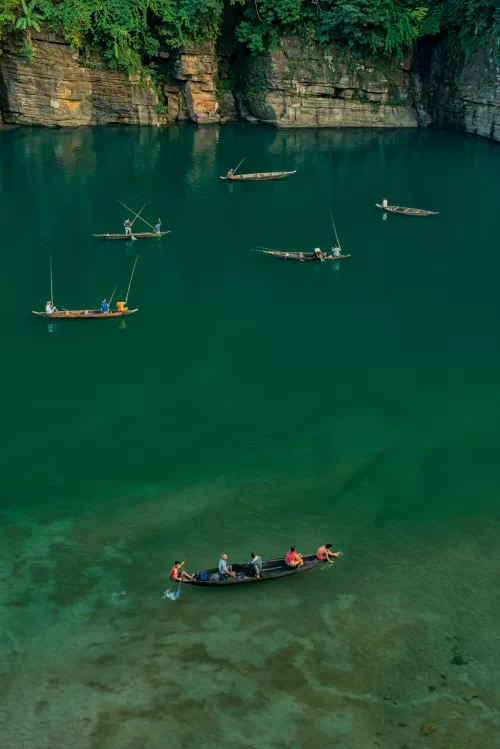 Crystal clear waters of Umngot River in Dawki Meghalaya with boats floating over transparent river featured in Meghalaya tour packages
