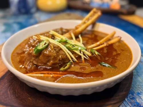 Nihari in slow-cooked rich spiced meat gravy garnished with ginger juliennes and green chilies, authentic Indian Mughlai cuisine with deep comforting flavors.