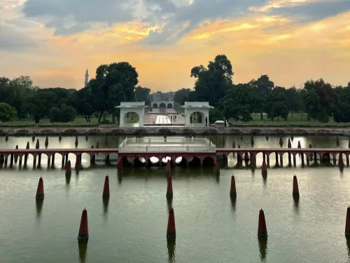 Shalimar Bagh pavilions at Nishat Garden Srinagar during sunset, featuring arched bridges, lake reflections and trees, perfect romantic experience in Srinagar tour package. 