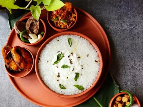 Pakhala Bhata with fermented rice topped with curd and curry leaves, served with traditional sides, authentic Indian Odia cuisine comfort food.