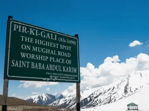 Peer Ki Gali signboard during sunny day, featuring Mughal road marker, snowy Pir Panjal mountains, perfect adventure experience Kashmir tour packages. 