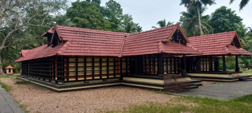 Sasthakulam Devi Temple in Kollam featuring traditional Kerala-style tiled roof, wooden lattice wall design, and serene green surroundings, perfect spiritual experience with Kerala tour package. 