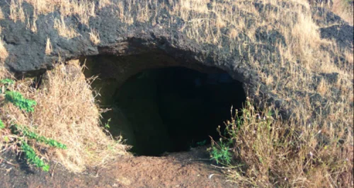 Gogarbha Shiva Cave in Baba Budangiri during daylight, featuring natural cave entrance and rocky terrain, perfect adventure experience, Karnataka tour packages. 