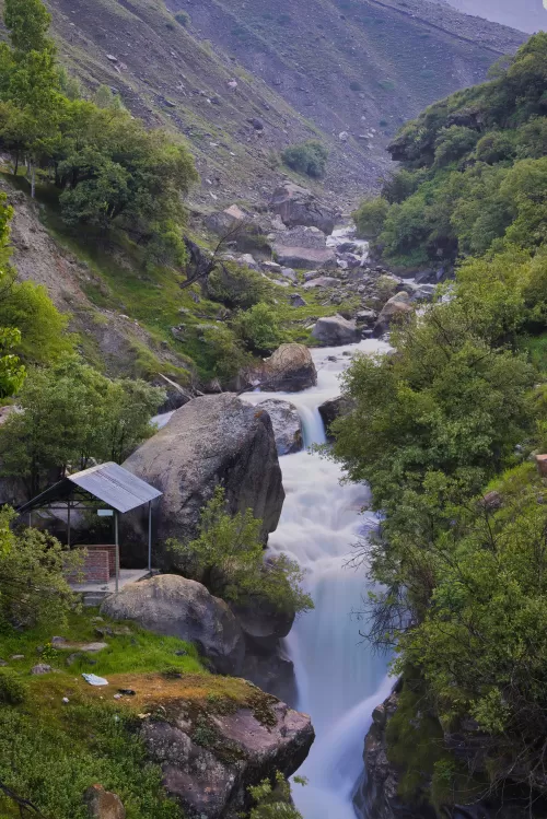 Mountain stream flowing through rocky valley with lush greenery in Sissu, a peaceful Himalayan escape featured in Himachal Pradesh tour packages.
