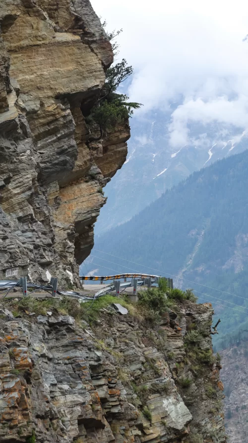 Dramatic cliffside view at Suicide Point in Kalpa, Himachal Pradesh, overlooking deep valleys and mist-covered Himalayan mountains, a breathtaking attraction included in Himachal Pradesh tour packages.