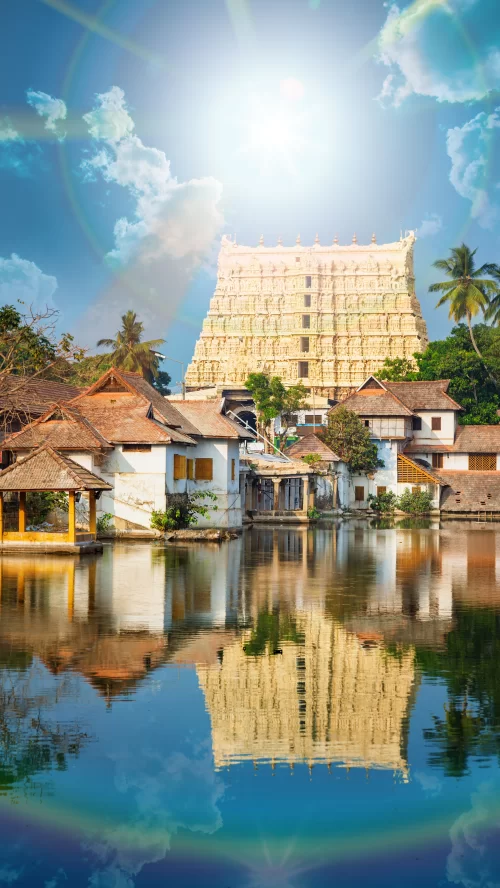 Sree Padmanabhaswamy Temple reflected in a serene temple pond in Thiruvananthapuram, Kerala, showcasing traditional architecture under a bright blue sky, a sacred landmark featured in Kerala tour packages.