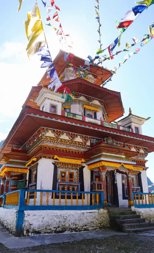 Colorful Buddhist monastery in Tawang Arunachal Pradesh adorned with prayer flags under clear sky featured in Arunachal Pradesh tour packages