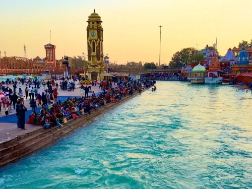 Har Ki Pauri Haridwar golden hour view of Hari ki Pairi clock tower crowded Ganga ghats devotees temples boats sunset sky, perfect aarti spiritual scene, Uttarakhand tour packages.