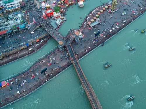 Har Ki Pauri Haridwar aerial top-down view of crowded Ganga ghats festival tents boats colorful stalls iron bridge during Kumbh Mela, perfect pilgrimage panorama, Uttarakhand tour packages.