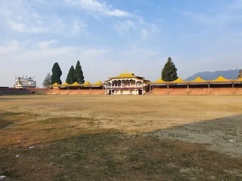 Buddha Stadium in Bomdila featuring yellow pavilions, wide sports ground, and scenic hill views, perfect Arunachal Pradesh tour package experience.