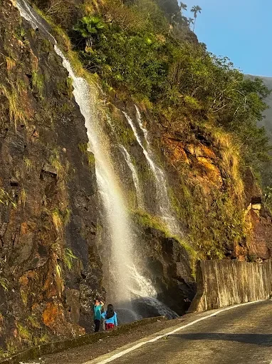 Khreng Khreng Falls in Mawsynram featuring cascading roadside waterfall, rocky cliffs, and lush green surroundings, perfect nature experience with Meghalaya tour package. 