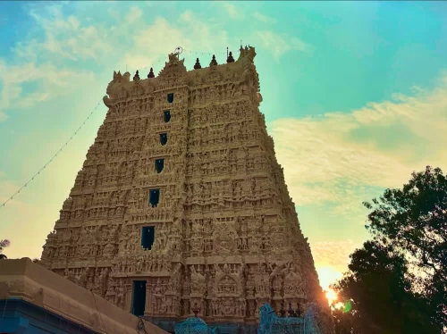 Towering gopuram of Suchindram Thanumalayan Temple during sunset, featuring intricate carvings and blue sky, perfect Kanyakumari tour package.